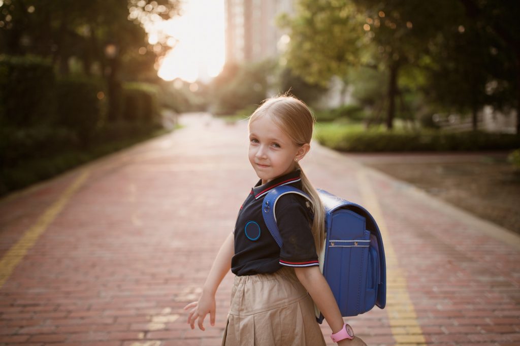 Back to school. Happy Little girl from elementary school outdoor.