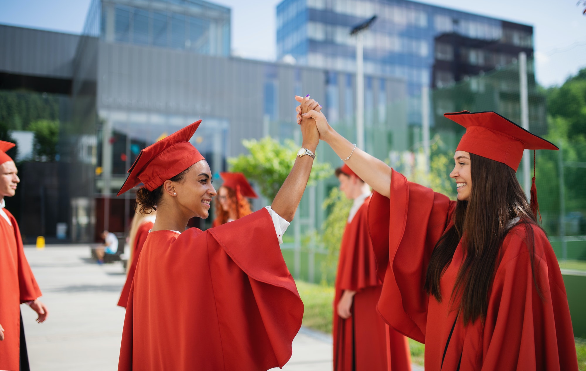 Group of cheerful university students celebrating outdoors, graduation concept