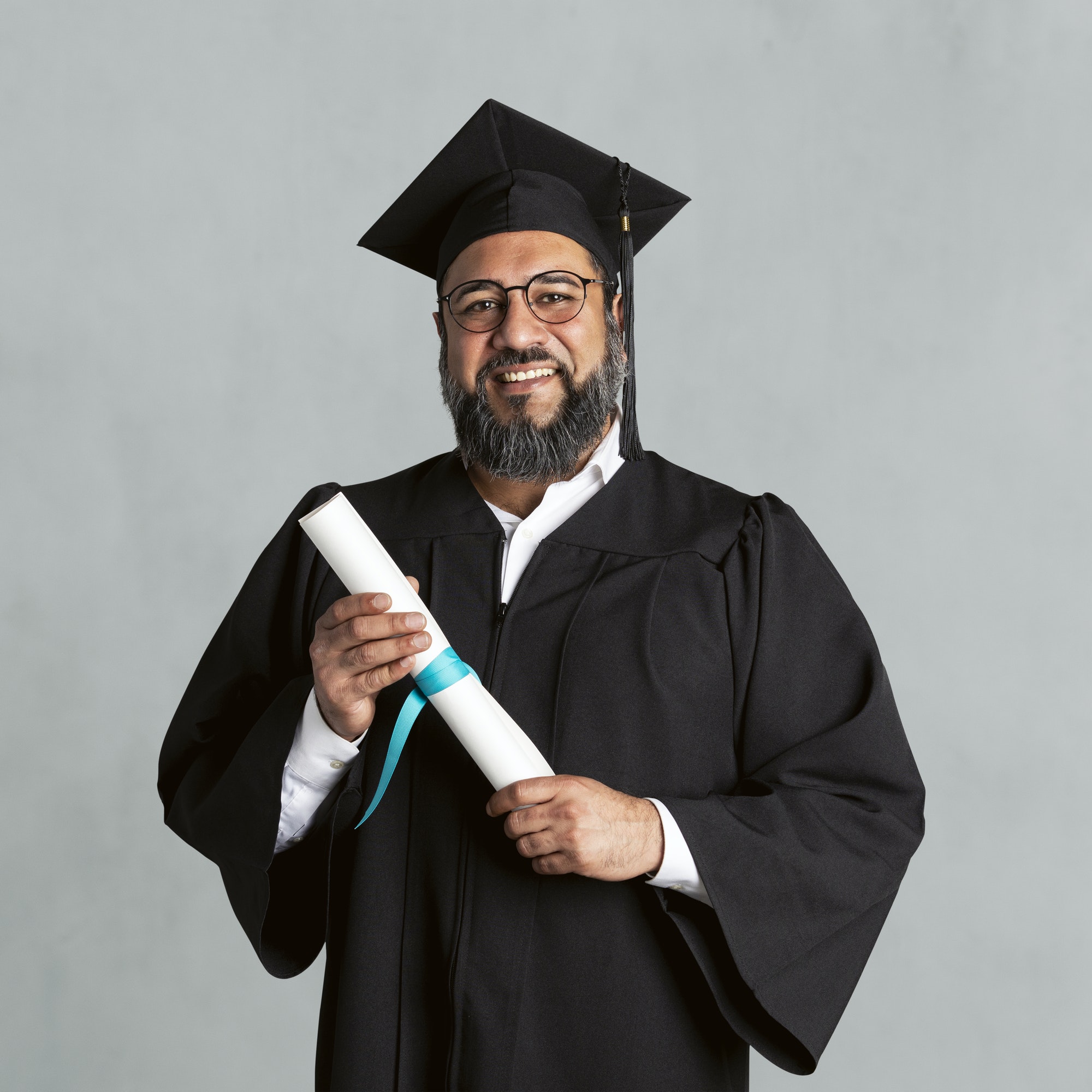 Happy senior man in a graduation gown holding his master's degree mockup