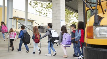 Elementary school kids arrive at school from the school bus